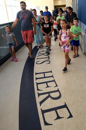 Parents and future students take a tour of the new Marathon Elementary School in Hopkinton Friday. The writing on the floor reads "It All Starts Here." [Daily News Staff Photo/Ken McGagh]