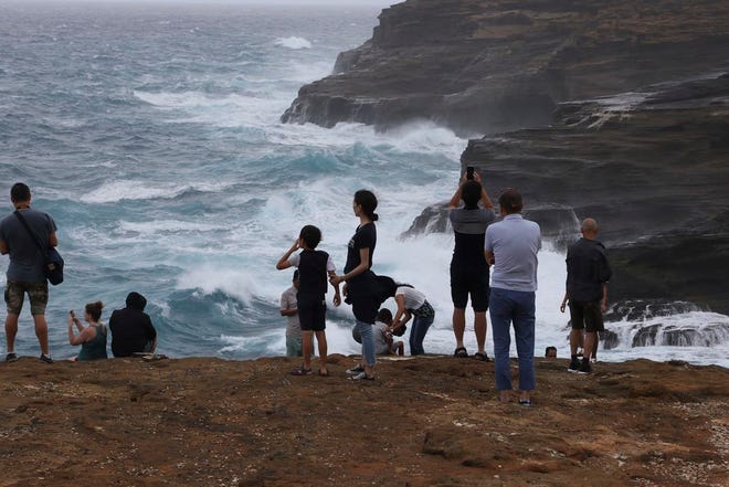 People stand along sea cliffs on the southeast shore of Oahu as Hurricane Lane approaches Friday, near Honolulu.