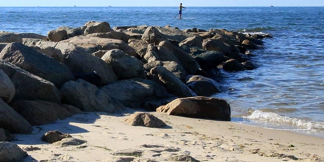 A paddle boarder glides by Brewster’s Point of Rocks Beach. [PHOTO BY WILLIAM F. POMEROY]