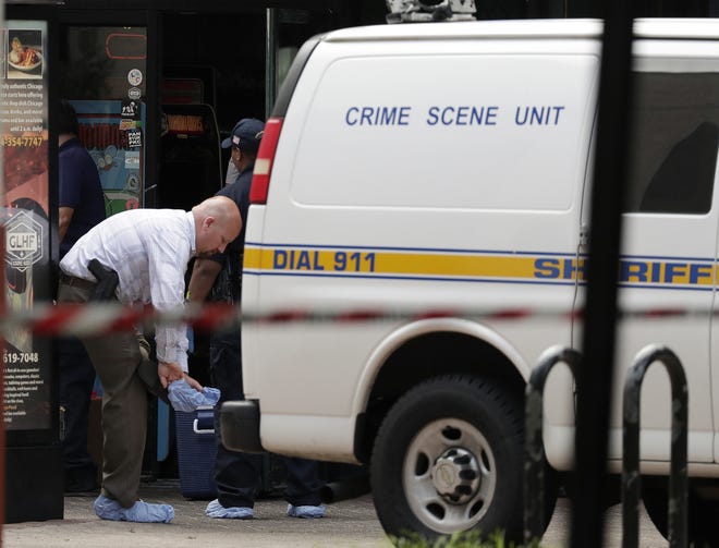 A law enforcement investigator puts protective covers over his feet Monday, Aug. 27, 2018, before entering a building that was the scene of mass shooting at The Jacksonville Landing in Jacksonville, Fla. A gunman opened fire Sunday at a video game tournament killing multople people and then fatally shooting himself in a rampage that wounded several others. (AP Photo/John Raoux)