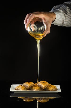 As the final step in making the traditional Greek dessert baklava, a honey syrup is poured over the baked pastry. [St. Louis Post-Dispatch / TNS / Ryan Michalesko]