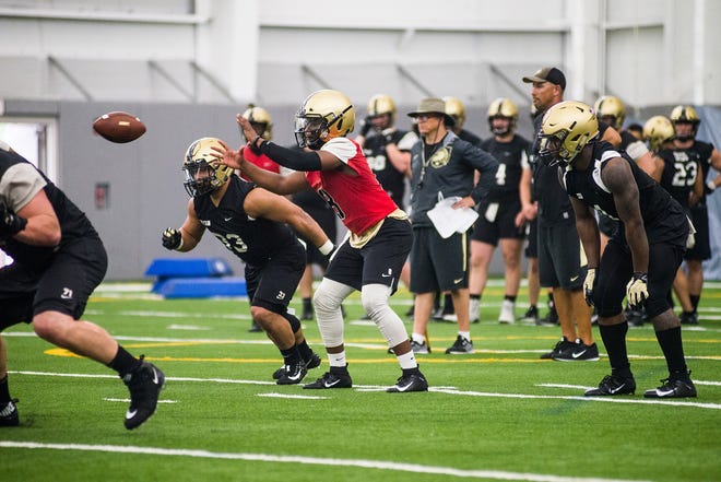 Army quarterback Kelvin Hopkins, in red shirt, takes the snap from center during the first day of practice on Aug. 2. The strong-armed junior was voted onto Army’s leadership council for this season. [KELLY MARSH/FOR THE TIMES HERALD-RECORD]