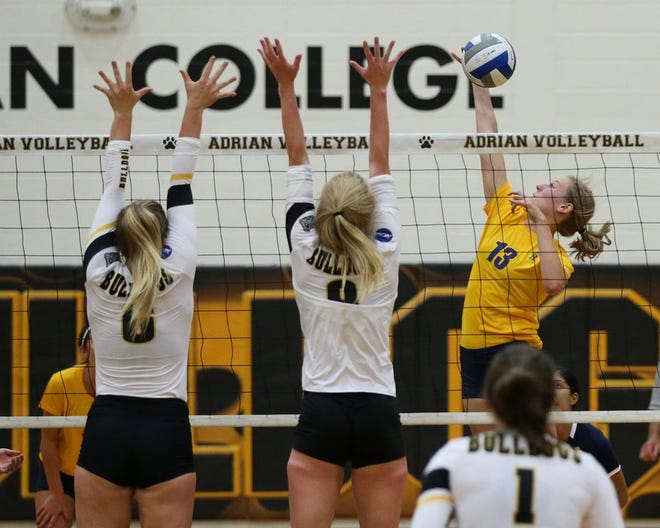 Siena Heights senior Christine Tylutki goes for a kill against a pair of Adrian College defenders during Tuesday's exhibition at the Merillat Sport and Fitness Center.