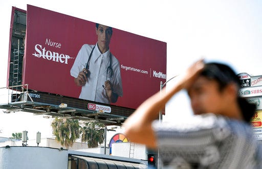 This May 9, 2018 photo shows a billboard for MedMen, a marijuana dispensary, at an intersection in Los Angeles. MedMen recently rolled out an ad campaign that featured photos of 17 people including a white-haired grandmother, a schoolteacher, a business executive, a former pro football player and a nurse, being splashed across billboards, buses and the web. (AP Photo/Chris Pizzello)
