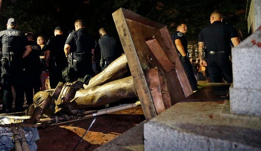 FILE - In this Monday, Aug. 20, 2018, file photo, police stand guard after the Confederate statue known as Silent Sam was toppled by protesters on campus at the University of North Carolina in Chapel Hill, N.C. A broadcast outlet reports a North Carolina police chief told his officers to stand aside as protesters tore down the Confederate monument. (AP Photo/Gerry Broome, File)