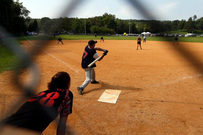 Photo by Daniel Freel/New Jersey Herald - Thomas Laird, of the Byram fire department, swings at bat as Jodi Bell, mother of a Frankford fire department member, pitches and Brittany Risdon, Frankford fire department auxiliary member, catches during the championship game of a slow-pitch softball tournament between county fire departments Sunday, August 26, 2018, in Branchville.