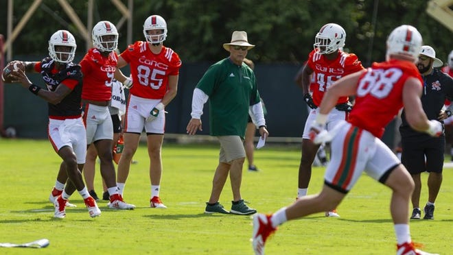 University of Miami quarterback N'Kosi Perry (5) throws a ball while head coach Mark Richt watches on during the first day of fall training camp at the Greentree Practice Fields in Coral Gables on Saturday, August 4, 2018.
