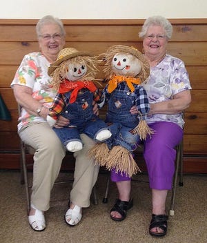 Look-alike sisters Ginger Bauman and Mimi Maxfield hold look-alike scarecrows they made for the Sept 15 Sugar Loaf United Methodist Church Fair, one of the first for the upcoming holiday season. [Photo provided]