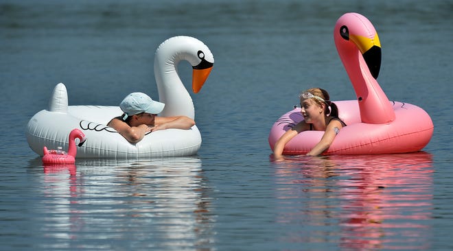 Kira Medeiros, left, of Natick, and her daughter Madeleine, 12, enjoy a peaceful Dug Pond in Natick aboard their swan and flamingo floats Tuesday. At left is a tiny flamingo float for their water bottles. Madeleine starts seventh grade at Wilson Middle School in Natick today. [Daily News Staff Photo/Ken McGagh]