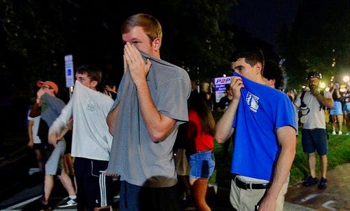 Protesters cover their faces after pepper spray is deployed behind Graham Memorial Hall on the campus of UNC-Chapel Hill, Thursday, Aug. 30, 2018, during a rally to commemorate the Confederate statue known as Silent Sam. (Chuck Liddy/The News & Observer via AP)
