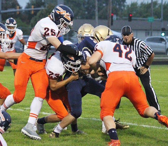 Keegan DeLong, (25), Nic Hendren (23) and Justin Grieff (42) gang up to tackle a Central Catholic ballcarrier during last week’s season-opening 35-14 win in Bloomington. The Indians open their home season Friday against Tolono Unity.