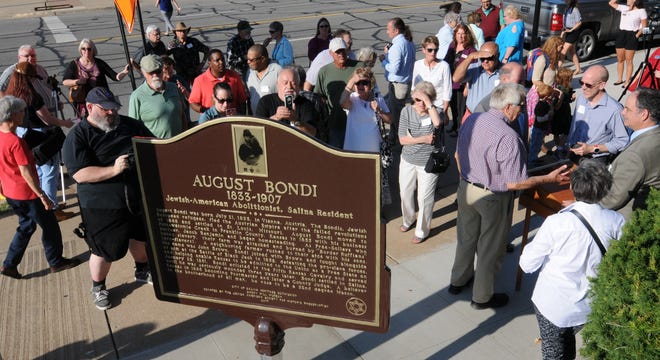 People gather Thursday afternoon to view a plaque honoring August Bondi. The plaque is located at the northeast corner of the Smoky Hill Museum. [TOM DORSEY / SALINA JOURNAL]