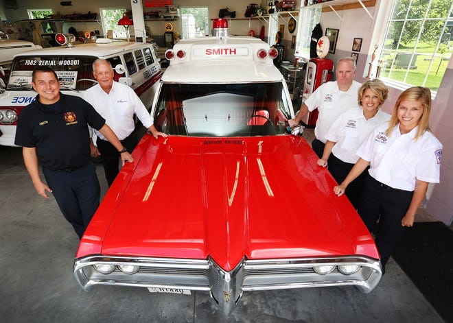 Three generations of paramedics in the Smith Ambulance family (l-r) Bob Smith, owner Robert Smith, Mike Mosser, his wife Kelli, and daughter Emily, pose in front of a 1968 Pontiac Superior High Top ambulance at their Dover facility Wednesday.(TimesReporter.com / Pat Burk)