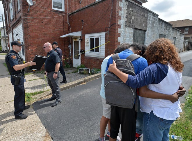 Four people, at right, pray near the scene of a suspicious death at 1061 E. 26th St. (background), in Erie on Thursday. East 26th Street was closed after a police crime scene unit arrived on the scene. [CHRISTOPHER MILLETTE/ERIE TIMES-NEWS]