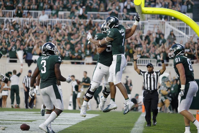 Michigan State's Cody White (7), LJ Scott (3), Matt Sokol (81) and Jordan Reid celebrate White's touchdown reception against Utah State during the second quarter of an NCAA college football game, Friday, Aug. 31, 2018, in East Lansing, Mich. (AP Photo/Al Goldis)