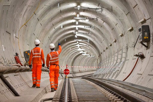 FILE - In this Sept. 14, 2017 file photo, Crossrail engineers walking alongside completed tracks. London's new east-west railway, Crossrail, says it will miss its scheduled December opening by almost a year, with passenger services not starting until late 2019. (Dominic Lipinski/PA via AP)