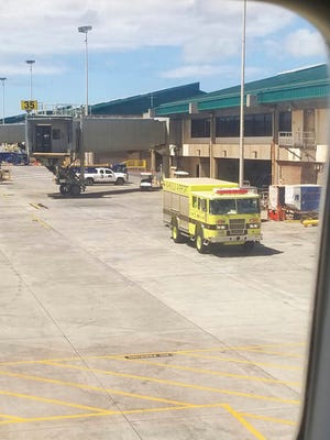 This Friday, Aug. 31, 2018 photo provided by Nicholas Andrade shows a fire truck outside a Hawaiian Airlines jet in Kahului, Hawaii, after a can of pepper spray went off inside the plane during a flight from Oakland, Calif. Twelve passengers and three flight attendants were treated for respiratory issues and released by emergency responders at the airport in Kahului, which is on the island of Maui. (Nicholas Andrade via AP)
