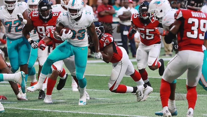 Miami Dolphins running back Kalen Ballage runs through the Atlanta Falcons defense, past linebacker Anthony Winbush for a touchdown and a 14-0 lead during the first quarter in a preseason game on Thursday, Aug. 30, 2018, at the Mercedes-Benz Stadium in Atlanta. (Curtis Compton/Atlanta Journal-Constitution/TNS)