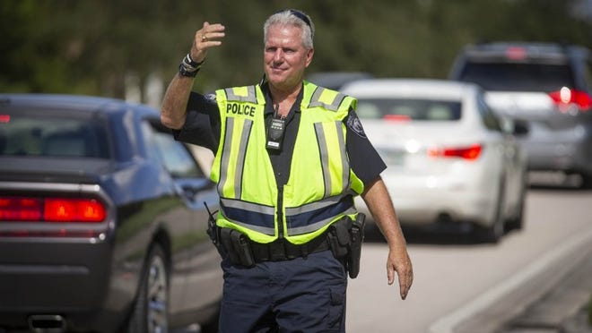 Palm Beach County School district officer Bob Keating is back to work directing traffic at the entrance to Wellington Landings Middle School. Last December, he was hit by a distracted driver while he was directing traffic and was seriously injured. He returned to duty nine months later and now is cautioning drivers to be attentive in school zones. (Allen Eyestone / The Palm Beach Post)