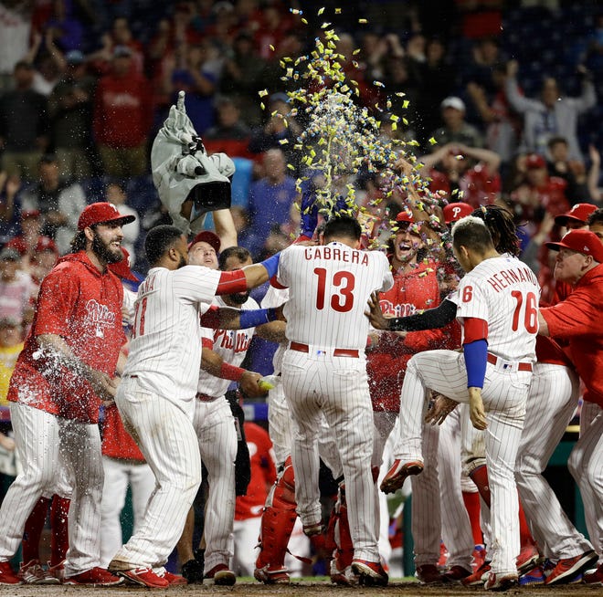 Philadelphia Phillies' Asdrubal Cabrera (13) is mobbed by his teammates after hitting the game-winning home run off Chicago Cubs relief pitcher Steve Cishek during the 10th inning Friday, Aug. 31, 2018, in Philadelphia. Philadelphia won 2-1. [MATT SLOCUM/THE ASSOCIATED PRESS]