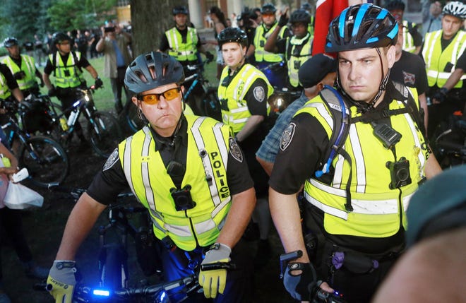 Police push bystanders aside with their bicycles as they lead 'Silent Sam' supporters into a a series of barricades to keep the public away from the statue supporters on every side of the statue's former site during ACTBAC's twilight vigil at UNC Chapel Hill on Aug. 30.

[Steven Mantilla/Times-News]