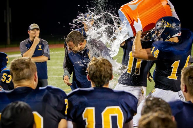Greencastle-Antrim's Thomas Hebert (14) and Max McDowell (11) dump the water cooler on head coach Devin McCauley after the Blue Devils' 42-7 victory over Camp Hill Friday night. The victory marked McCauley's first as head coach of the Blue Devils.