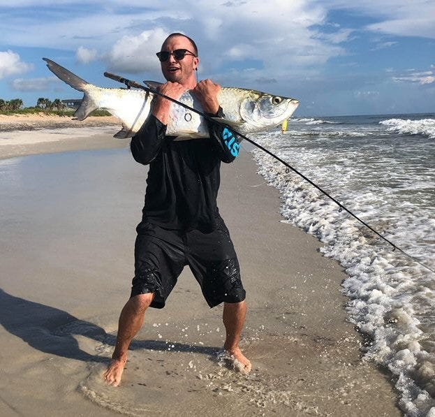 Jacksonville's Derek Fox holds a 38-inch, estimated 40-pound tarpon that he caught while fishing in the surf near St. Augustine. The mullet run has begun, and tarpon, redfish and many other species are gorging on the baitfish as they mass and migrate near the surf, and in area inlets and river mouths. [Dave Gill, Special to the Times-Union]