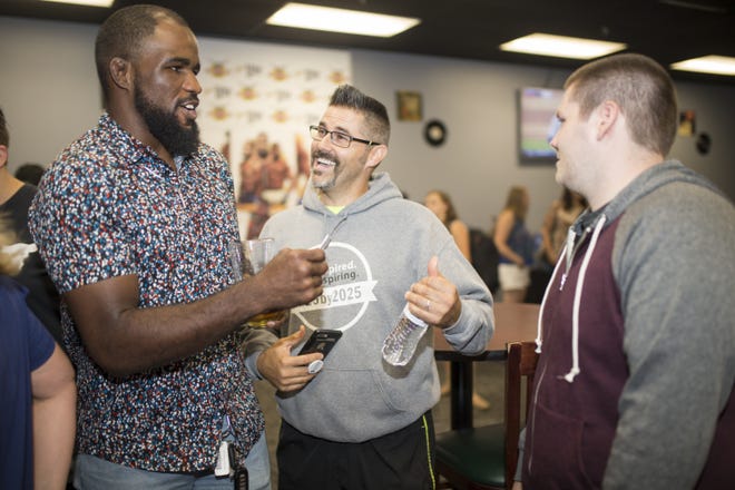 Corey Anderson, left, a Rockton native and Ultimate Fighting Championship star, greets friends and fans like Jim McIlroy of Rockford, center, and his son Landis on Friday, Aug. 31, 2018, at the Stockyard Rock Burger Bar in Rockford. [SCOTT P. YATES/RRSTAR.COM STAFF]