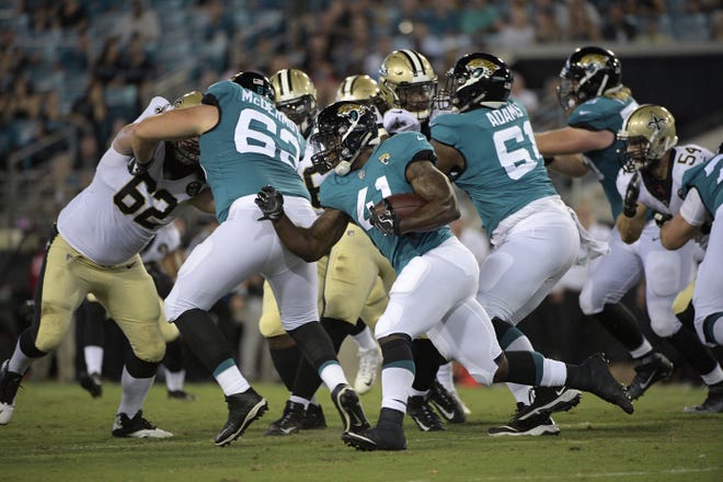 Jaguars running back Tim Cook (41) rushes for yardage as offensive tackle KC McDermott (62) blocks during a preseason game. Both players were cut Saturday. [Phelan M. Ebenhack/The Associated Press]