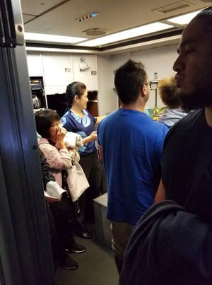 This Friday photo provided by Nicholas Andrade shows people gathered in a back galley on a Hawaiian Airlines flight from Oakland, Calif., to Kahului, Hawaii, after a can of pepper spray went off inside the plane. Twelve passengers and three flight attendants were treated for respiratory issues and released by emergency responders at the airport in Kahului, which is on the island of Maui.