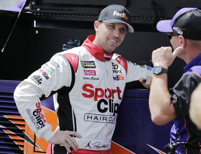 Denny Hamlin talks with a crew member on pit road before winning the pole for Sunday's race at Darlington Raceway. Hamlin posted a fast lap of 173.571 mph. [The Associated Press]