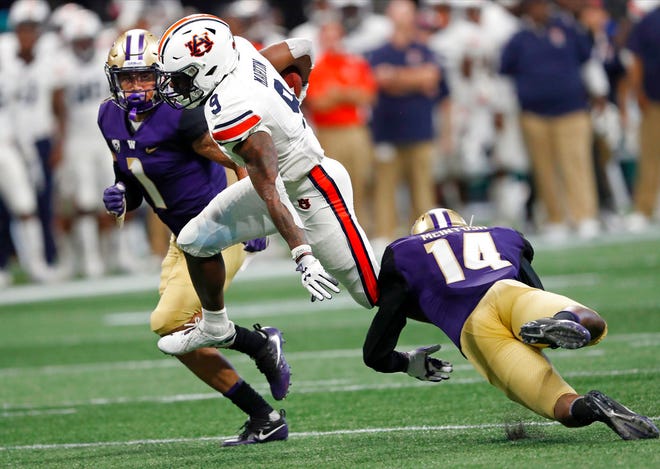 Auburn Tigers running back Kam Martin (9) tries to get past Washington's JoJo McIntosh (14) and Byron Murphy (1) in the first half of an NCAA college football game Saturday, Sept. 1, 2018, in Atlanta. (AP Photo/John Bazemore)