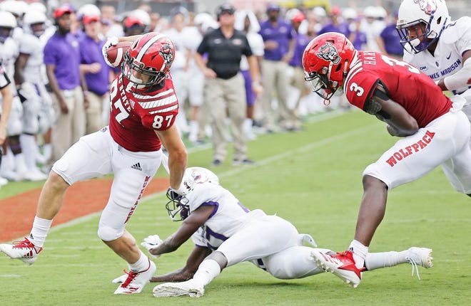 North Carolina State's Thayer Thomas breaks the tackle attempt by James Madison's Taurus Carroll as North Carolina State's Kelvin Harmon, right, moves in.
