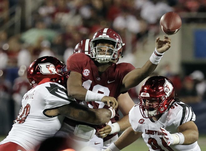 Alabama quarterback Tua Tagovailoa, center, manages to get off a pass as he is hit by Louisville defensive lineman Jared Goldwire, left, and defensive end Derek Dorsey (91). The top-ranked Crimson Tide won 51-14. [John Raoux/The Associated Press]