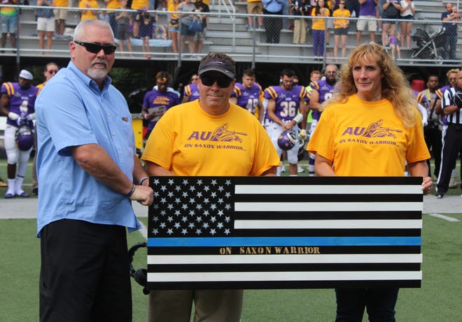 Alfred University football coach Bob Rankl, center, presents a custom flag to Trooper Nick Clark's parents, Anthony Clark and Theresa Gunn, during a special ceremony before Saturday's season opener. [Chris Potter/The Spectator]