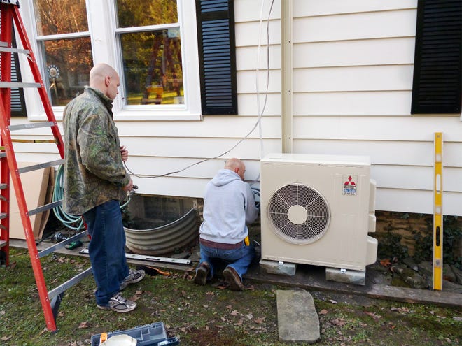Dave Tierno and an employee with Air Source LLC in Greene install an air source heat pump on an oil-heated home in Cooperstown in 2012. [SUBMITTED PHOTO]