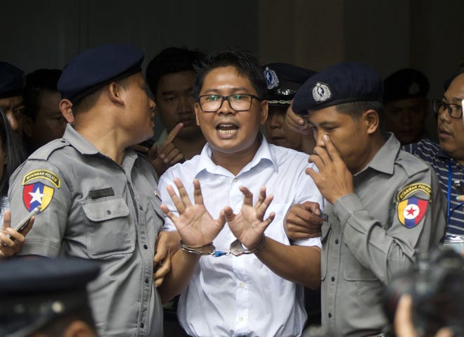 Reuters journalist Wa Lone, center, talks to journalists as he is escorted by police to leave a court in Yangon, Myanmar Monday, Sept. 3, 2018. The court in Myanmar has sentenced two Reuters journalists to seven years in prison for illegal possession of official documents, a ruling that comes as international criticism mounts over the military's alleged human rights abuses against Rohingya Muslims. (AP Photo/Thein Zaw)