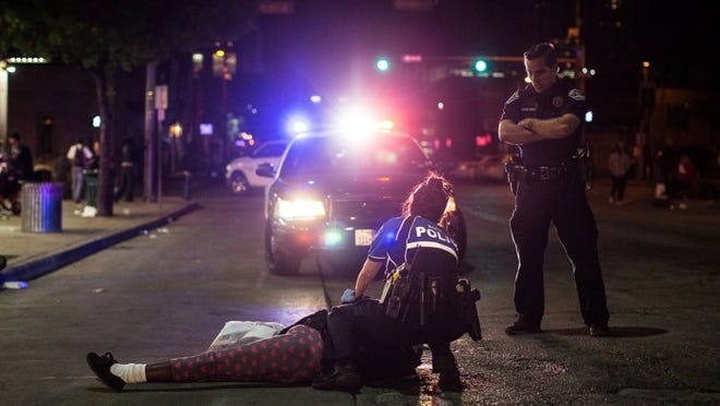 Austin police tend to a women who had collapsed in front of the Austin Resource Center for the Homeless in 2017. Police say she like lost consciousness after using synthetic marijuana.
