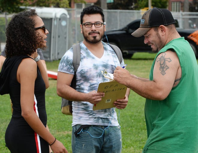 From left, Young Democrats Makayla Alicea, 20, and Victor Ruiz, 28, help Luis Lopez, 37, register to vote in Erie on Aug. 25. [GREG WOHLFORD/ERIE TIMES-NEWS]