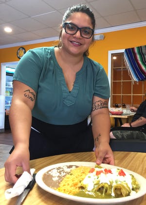 Valery Rogel serves a plate of enchiladas at Tacos el Nevado whiich opened recently in Shelby. [Diane Turbyfill/The Star]