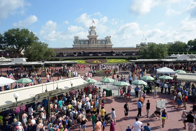 In this June 15, 2016, file photo, guests appear at the entrance to Disney's Magic Kingdom theme park in Lake Buena Vista, Fla. Disney is offering to pay full tuition for hourly workers who want to earn a college degree, finish a high school diploma or learn a new skill. The company said Wednesday, Aug. 22, 2018, that starting in the fall it will pay upfront tuition to workers who want to take classes through UF online. [AP Photo]