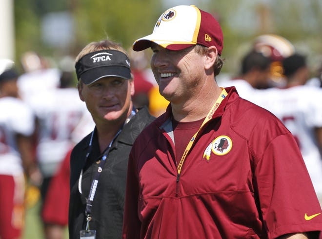 Jon Gruden, left, walks with his brother, Washington Redskins head coach Jay Gruden, after practice in 2014 in Richmond, Va. With Jon returning to the sideline after a decade away, and Jay entering his fifth season, they will join the Harbaughs as the only sets of siblings to simultaneously hold jobs as NFL head coaches. [AP Photo, File]