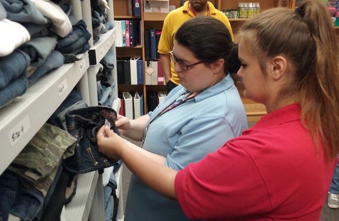 Jamie Gomez, left, and Alexis French check the size on a pair of jeans to make sure it is correctly shelved in the STUFF Bus storage room at Indian Trails Middle School. [NEWS-TRIBUNE/SHAUN RYAN]