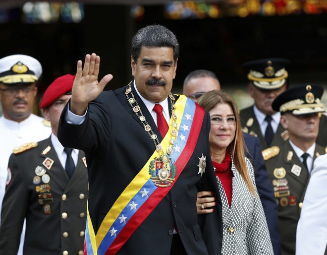 Venezuela's President Nicolas Maduro and first lady Cilia Flores greet the media as they arrive to a military parade May 24 at Fort Tiuna in Caracas, Venezuela. [Ariana Cubillos/thehawkeye.com]