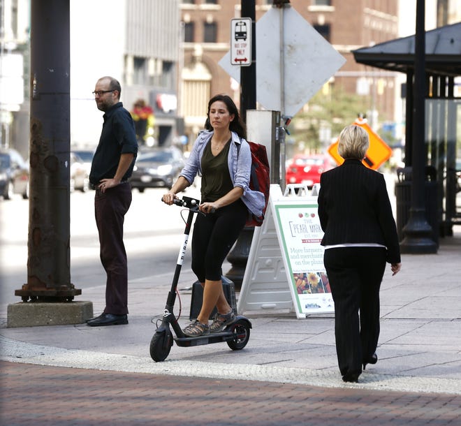A woman riding a scooter crosses S. High Street at Broad Street downtown Aug. 28. (GateHouse Media Ohio / Fred Squillante, Dispatch)