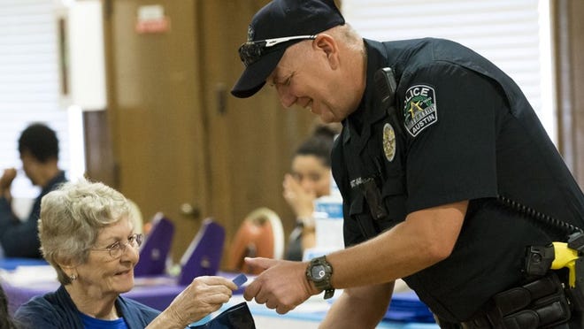 Austin police officer James Hyatt hands a door prize to Joyce Evans at the 2018 Seniors and Law Enforcement Together safety fair at the Lamar Senior Activity Center on Friday. LYNDA M. GONZALEZ / AMERICAN-STATESMAN