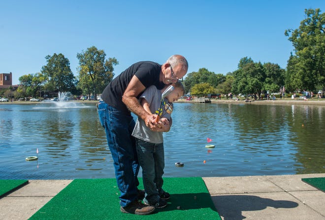 DAVID ZALAZNIK/JOURNAL STAR FILE PHOTO Xander Simply, 6, of Hanna City, gains a few tips from his grandfather, Kenny Chance, of Marquette Heights, while trying his hand at Lagoon Golf at the Pekin Marigold Festival in Pekin.