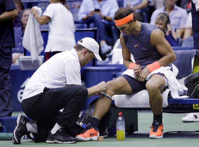 Rafael Nadal is treated by a trainer during a change over against Juan Martin del Potro during the semifinals of the U.S. Open on Friday in New York. [AP PHOTO/SETH WENIG]