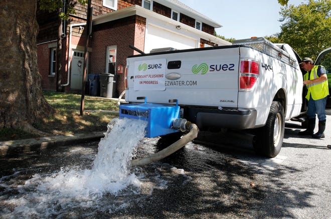 A Suez Water employee flushes and tests water from a hydrant in front of the fire station in South Kingstown last week. [The Providence Journal / Kris Craig]