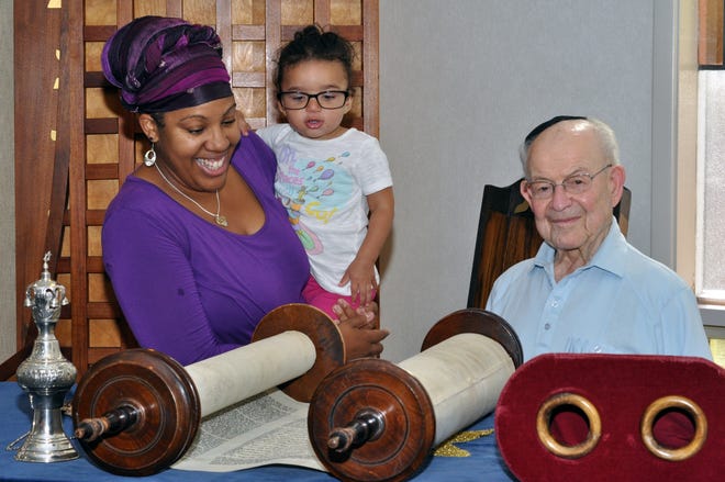 Rabbi Tiferet Berenbaum assists Ernest Kaufman remove a Torah scroll from the ark while holding her 1-year-old daughter Galya at Temple Har Zion in Mount Holly. [COURTESY OF JOEL BERENBAUM]